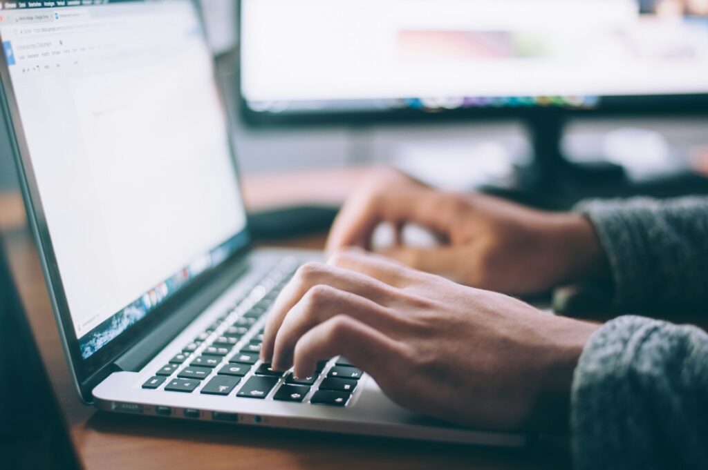 Hands typing on a laptop, focused on transcription.